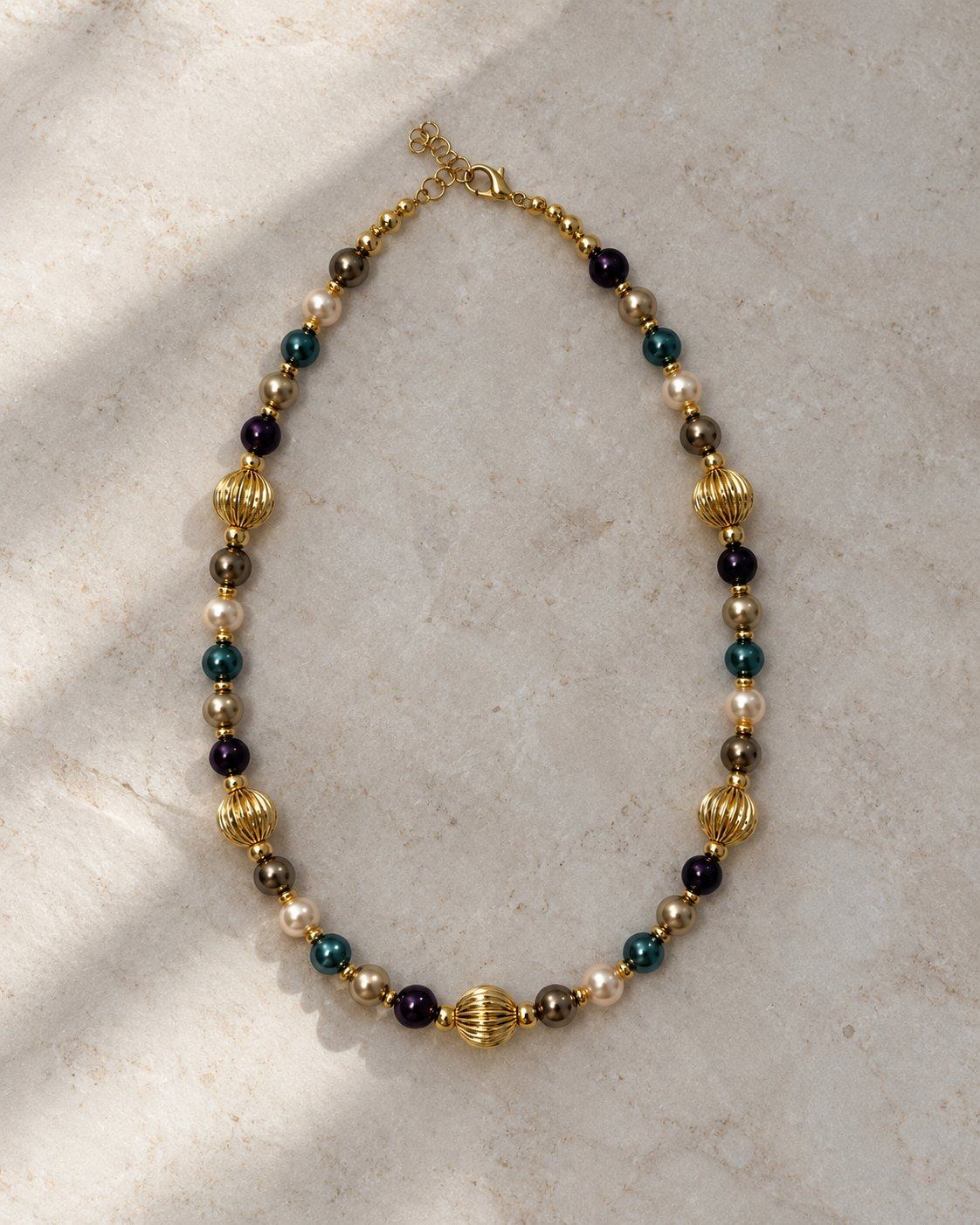 Nanshe necklace laid flat on pale grey marble.